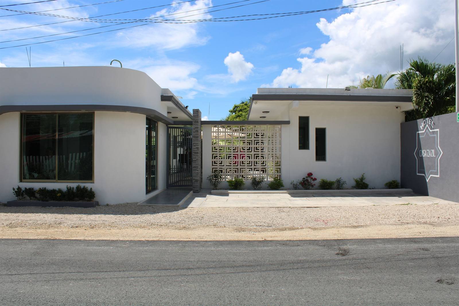 White single-story facade of Casa Zazil with a gate and a small garden