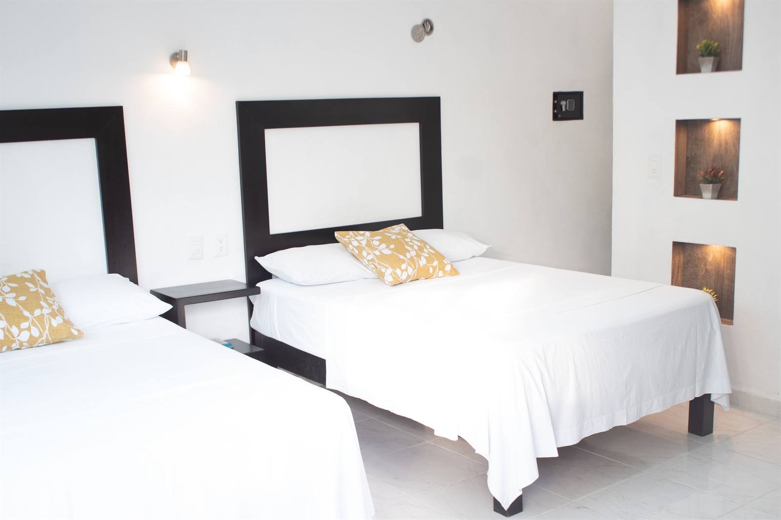 Bright room with two beds, white bedding and lit wall niches
