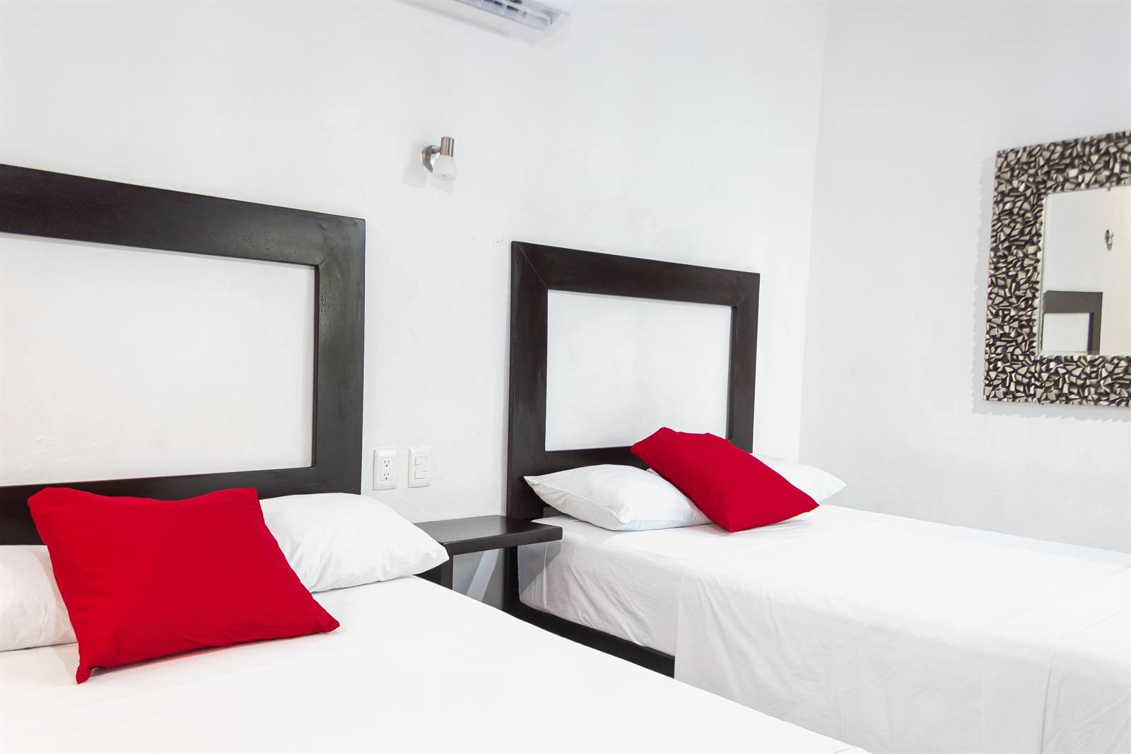Room with two beds, red cushions and a decorative mirror
