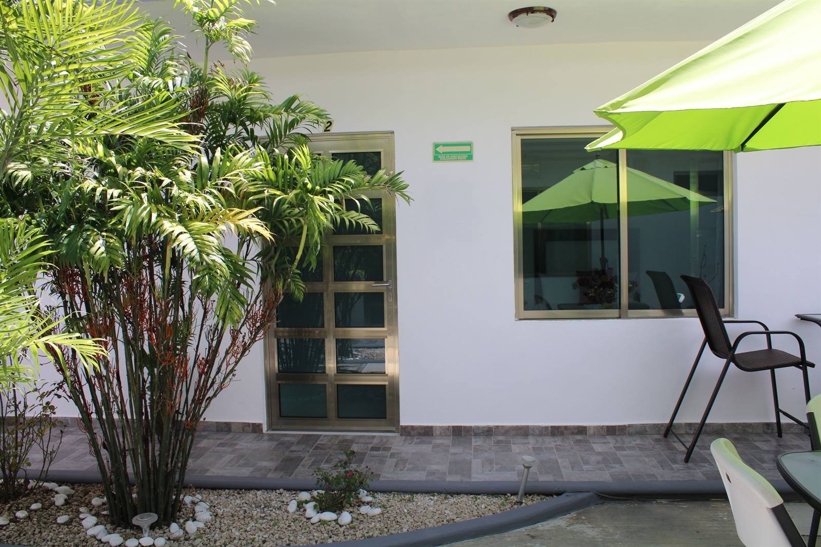 Outdoor seating with a green umbrella outside the rooms